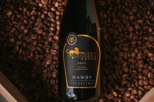 Photo of a bottle that says panther coffee on top of coffee beans