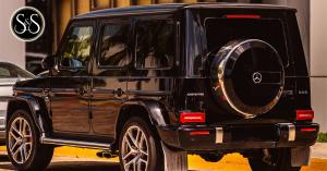 A black Mercedes-Benz G-Wagon parked at curb with rear facing viewer