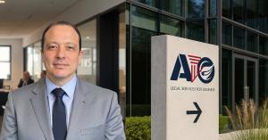 Portrait of Ahmed Othman, Lawyer, standing in a modern office with the AIO Legal Services office sign beside him.