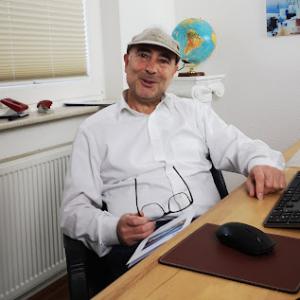 Dimitrios Zachos sitzt an seinem Schreibtisch im Büro, Gründer der TCM Gruppe mit griechenlandabc.de und Experte für maßgeschneiderte und mit Preisen ausgezeichnete Griechenland-Reisen.