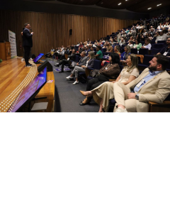 Rony Jabour speaking onstage to a full auditorium during his CONEST 2025 keynote, with attendees seated and listening attentively in Brasília, Brazil.