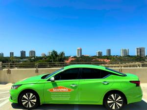 Bright green SERVPRO branded vehicle with Naples/Marco Island location information parked with Naples, Florida skyline in background