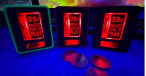 Three illuminated TinyBrights™ Insert Coin Cubes in different cube colors, displaying the red “25¢ Insert Coin to Play” button with arcade coins in front.