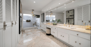Luxury primary bathroom featuring marble surfaces, sophisticated lighting, expansive vanity, and seamless access to a serene private patio garden.