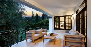 Luxury terrace with designer lounge furniture, lush tree-top backdrop, and ambient sunset lighting.