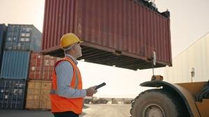 man with cargo container lifted by a crane