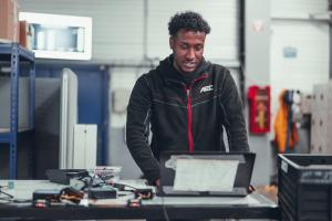 AEC technician working on vehicle systems and digital documentation inside the workshop.
