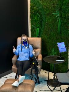 A patient seated comfortably in a recliner at MetaLab undergoing Resting Metabolic Rate (RMR) testing with a PNOĒ metabolic analyzer mask, relaxing in a calm, spa-like environment.