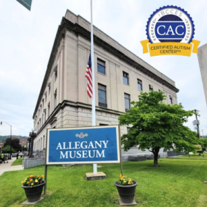Exterior view of the Allegany Museum with the American flag at half-mast and colorful flower pots by the entrance.