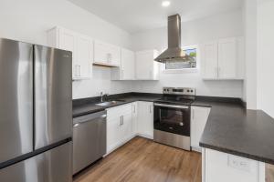 A new kitchen with white cabinets, stainless steel energy efficient appliances, and wood floor.