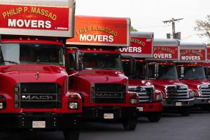 Row of red Philip P. Massad Movers Mack trucks lined up showing the company's professional moving fleet in Massachusetts