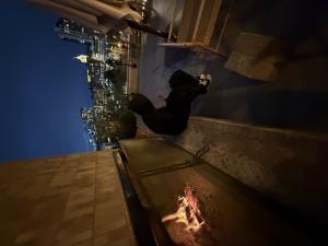 Martyn Kingsley sitting near an outdoor fireplace on a rooftop terrace with the city skyline in the background at night.