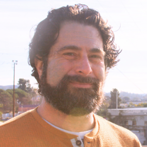 Loren Colin stands on the North Broadway Bridge facing west toward Chinatown with Lincoln Heights behind him.