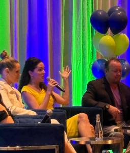 Dominique training franchisors on innovative ways to create growth in their systems. Sitting on stage at a conference.