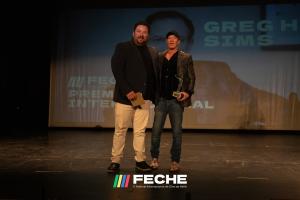 Greg H. Sims stands on stage at the  V Festival Internacional de Cine de Hellin, FECHE 2025 Edition, accepting the Premio Internacional Award.