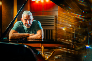 Composer Paul Dinletir behind his piano at his Los Angeles studio
