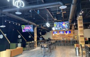 Golf Lounge 18 - Indoor golf and entertainment lounge shown with televisions, full bar, and seating.