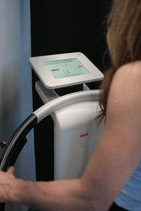 A patient uses the SECA Body Composition Analyzer while the touchscreen confirms proper hand and foot electrode connections, ensuring accurate bioimpedance readings during the scan at MetaLab.