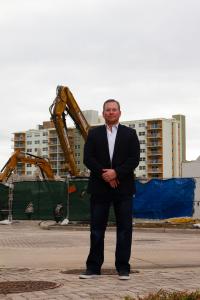 Andrew Beachler, CEO of Beachler Investments, standing in front of excavators at a redevelopment site in Fort Lauderdale, Florida, with apartments in the background.