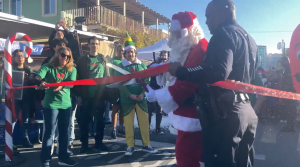 Megan Klein, 2025 LATLC President and Newton Division LAPD Captain Keith Green helping Santa Claus cut the ribbon at LATLC's 10th Annual Comfort & Joy, "A Miracle on 34th Street" at St. Patrick's Church