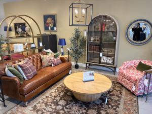 Ballard Designs store living room vignette with brown leather sofa and round coffee table.