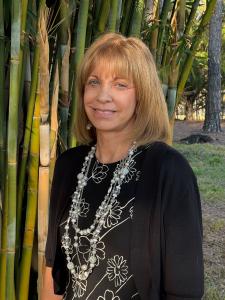 headshot of blonde woman standing near tree