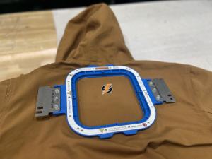 Magnetic hooping frame attached to a heavy winter jacket, holding the fabric securely for embroidery.