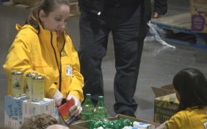 Volunteers work in the warehouse packing boxes with food.