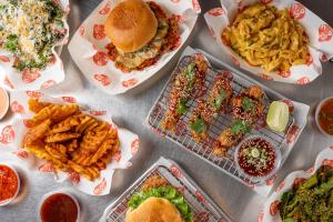 Tender Crush dishes including crispy tenders, chicken sandwiches, waffle fries, truffle mac and cheese, kale salad, broccolini, and sauce dips