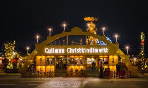 World's largest walk-on Christmas arch illuminated at night, displaying 'Cullman Christkindlmarkt' with traditional German wooden figurines and candle decorations in golden-lit display windows