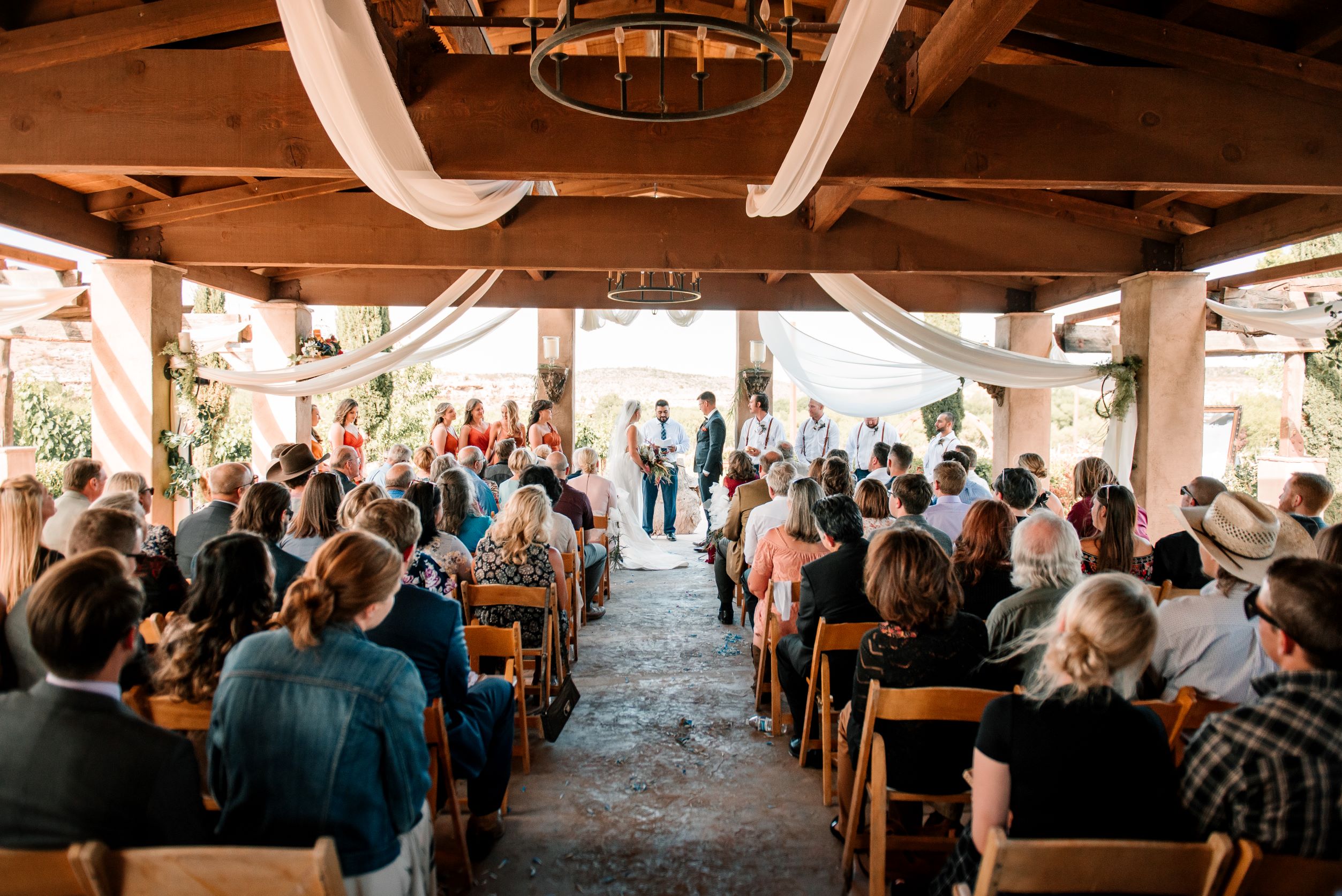 Wedding ceremony taking place in the Chapel Ruins at Alcantara Vineyards with draped fabric, vineyard backdrop, and guests seated inside the structure.