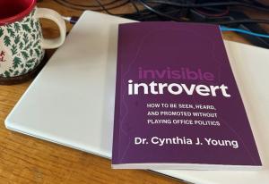 "Invisible Introvert" book lying on white laptop computer.