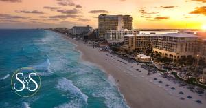 Blue water and white crested waves on the shores of Cancun Mexico at sunset with beautiful hotels entertaining guests