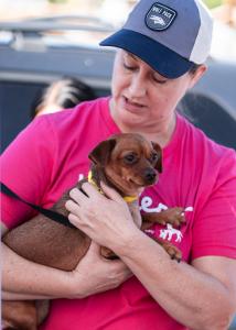 Photo of Dr. Wilson at a community vaccine clinic holding a small dog to her chest for decorative purposes.