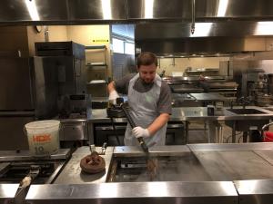 Commercial kitchen deep cleaning technician performing detailed equipment sanitation during an on-site service.