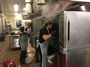 Kitchen steam cleaning in progress, addressing grease buildup behind commercial cooking equipment in a regulated facility.