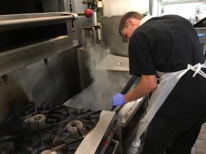 Steam-based commercial kitchen deep cleaning targeting hard-to-reach areas beneath and behind cooking equipment.