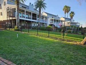 Black ornamental iron fence installed along a waterfront residential property in St. Tammany Parish with homes and palm trees in the background