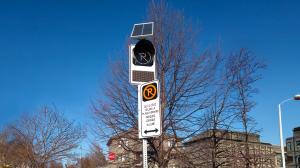 Dynamic parking sign installed on a city street in Laval, showing an illuminated parking restriction symbol used for winter operations.