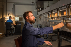 Testing building materials using a Steiner Tunnel. To achieve the ASTM E2768 results required by building codes, the flame front must not progress beyond 10.5 feet at any time during the test's 30-minute duration.