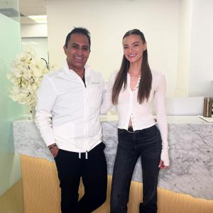 Dr. Borzoo poses with smiling patient in front of his reception area.