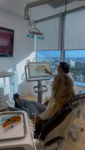 Dr. Borzoo consults with patient about their teeth using a 3D scan on a monitor.