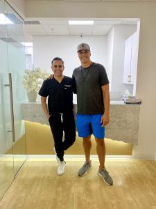 Dr. Borzoo poses with another smiling patient in front of his reception area.