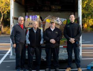 Members of Slug-A-Bug’s team stand in front of a truck full of food items the company collected for the Share Your Christmas food drive.