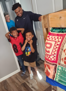 Sleep in Heavenly Peace volunteers deliver a hand-built wooden bunk bed with new mattresses, pillows and locally handmade quilts, to excited children during Deliveries Across America 2025, the nation's largest single-day bed delivery event ending child be