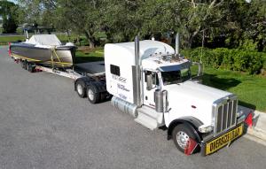 Genesis Exotic Transport carrier moving a luxury yacht across the U.S., showcasing secure and insured nationwide boat transport services.