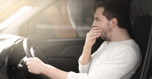 Adult man sitting in a vehicle with hand near his face, appearing tired and stressed, representing working adult fatigue during high-demand periods.