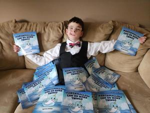 Young adult Drew Patchin surrounded by copies of his book, Marshmallow Can Do Hard Things