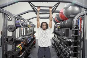 Single male exerciser hanging from center bars.