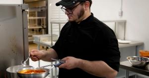 Richard Patti, owner of Kali Vita Fresca, stands at a commercial stove preparing Mediterranean-inspired dishes inside Frontier Kitchen, a shared kitchen space in Sharpsburg, Pennsylvania.